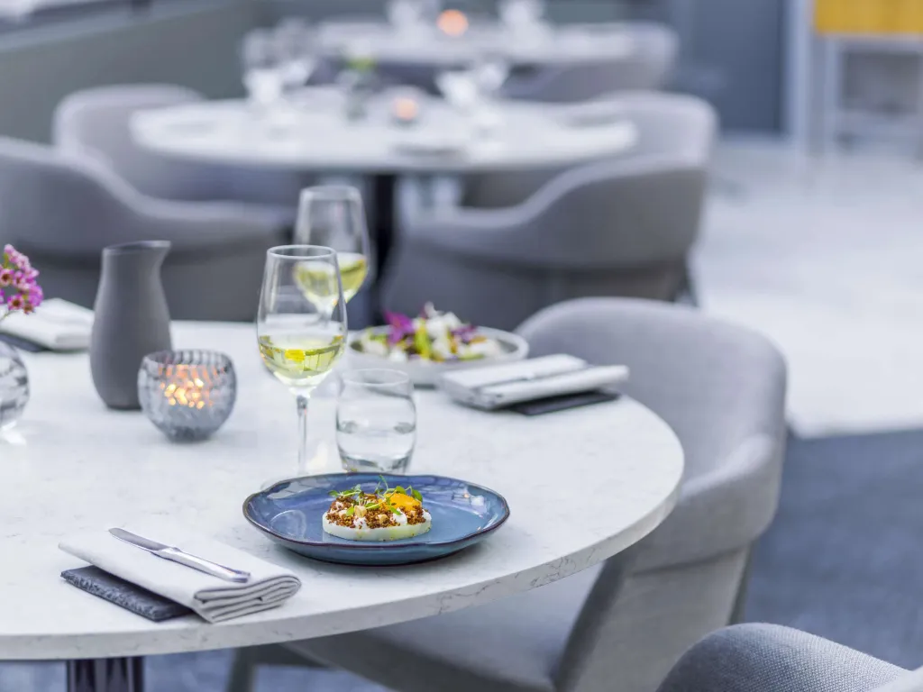 Une table est dressée avec un plat raffiné et des verres.