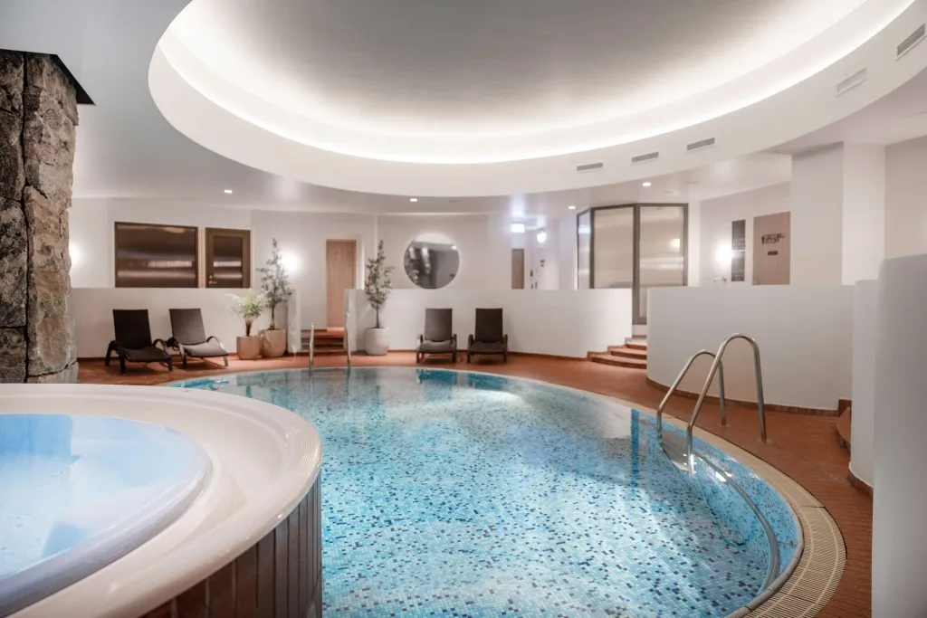 Piscine intérieure lumineuse avec transats et escalier d'accès.