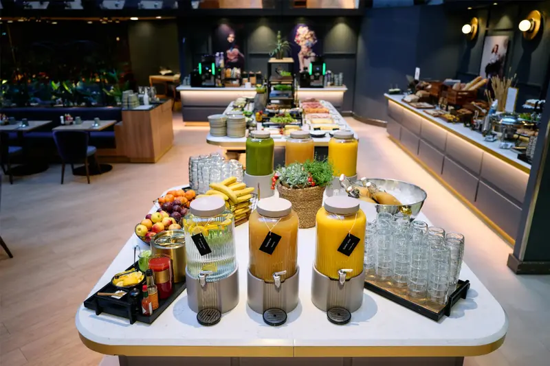 Un buffet propose des jus de fruits frais, des fruits et une variété de plats.