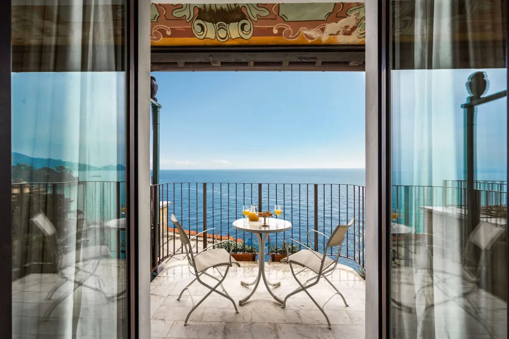 Une table ronde avec des verres est placée sur une terrasse offrant une vue sur la mer.