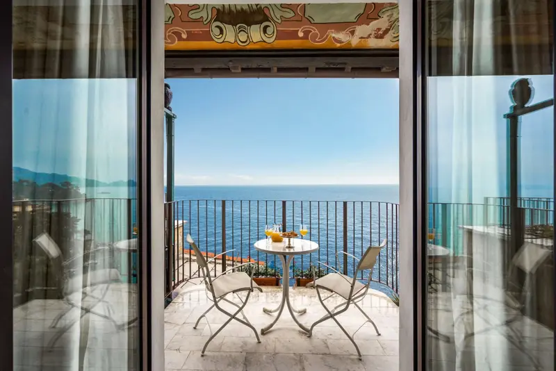 Une table ronde avec des verres est placée sur une terrasse offrant une vue sur la mer.