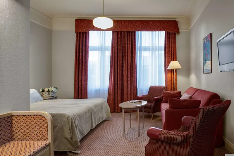 Une chambre lumineuse avec un lit et un coin salon.