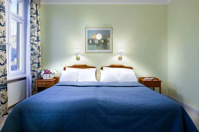 Une chambre lumineuse avec un grand lit recouvert d'une couverture bleue.