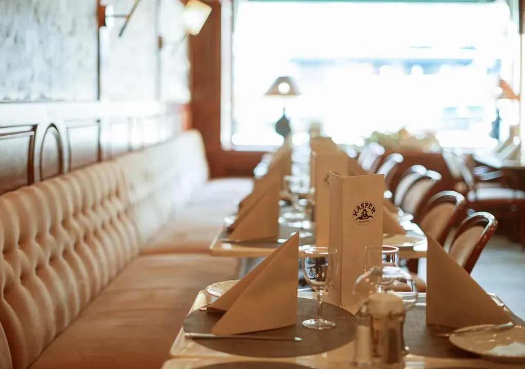 Une salle de restaurant avec des tables dressées et des banquettes en tissu.