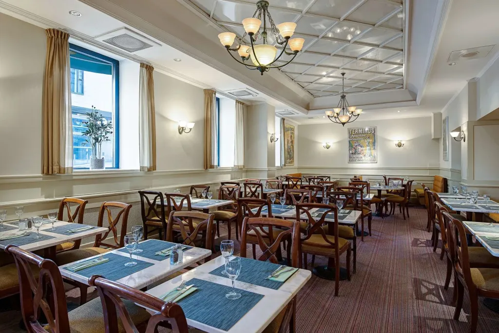 Une salle lumineuse avec des tables dressées pour un repas.