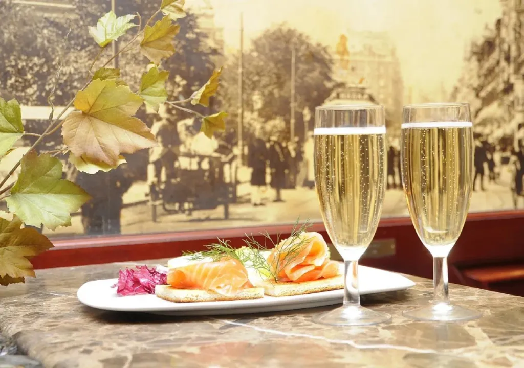 Deux coupes de champagne accompagnent une assiette de canapés au saumon.