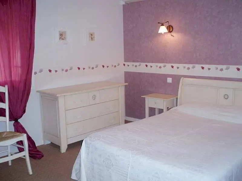 Une chambre lumineuse avec un lit recouvert d'une courtepointe et une commode.
