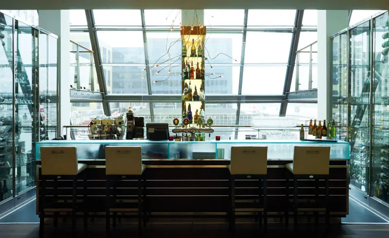Un comptoir de bar moderne avec des tabourets, devant une grande baie vitrée.