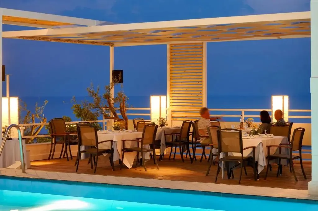 Tables dressées en terrasse avec vue sur la mer au crépuscule.