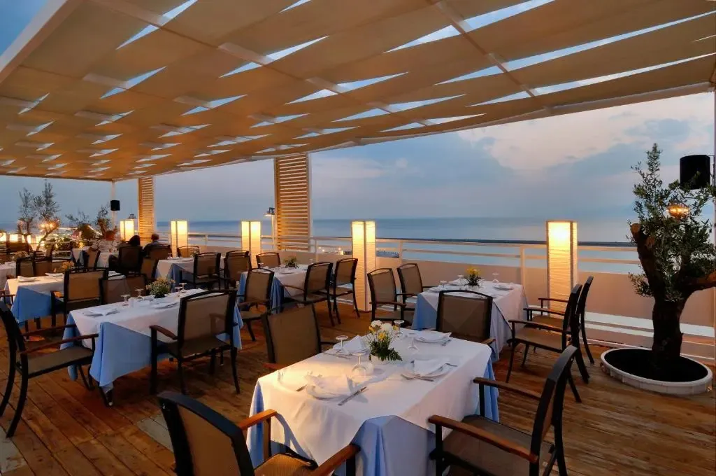 Terrasse de restaurant avec tables dressées face à la mer.