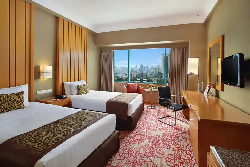 Chambre avec deux lits et vue sur la ville.
