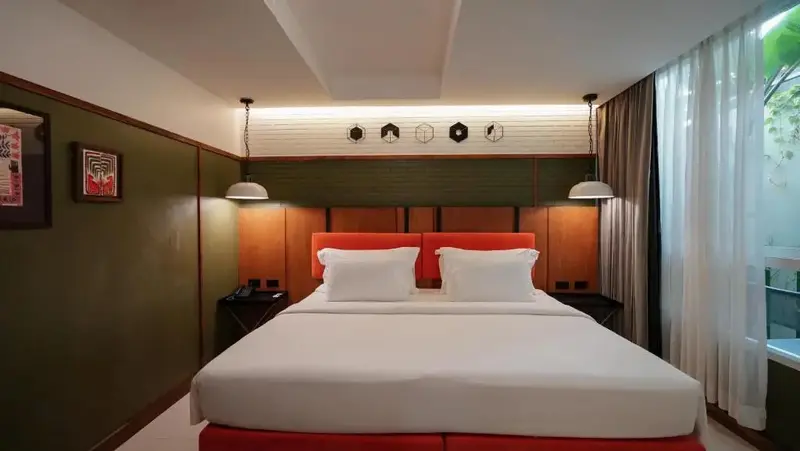 Une chambre lumineuse avec un grand lit et une décoration murale.