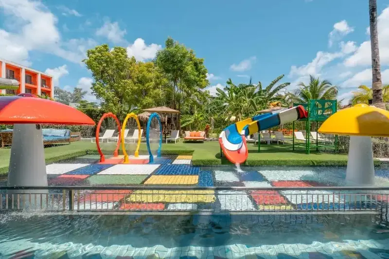 Une piscine pour enfants avec toboggan et jeux d'eau, entourée d'une végétation luxuriante.