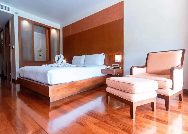 Une chambre lumineuse avec un grand lit et un fauteuil.