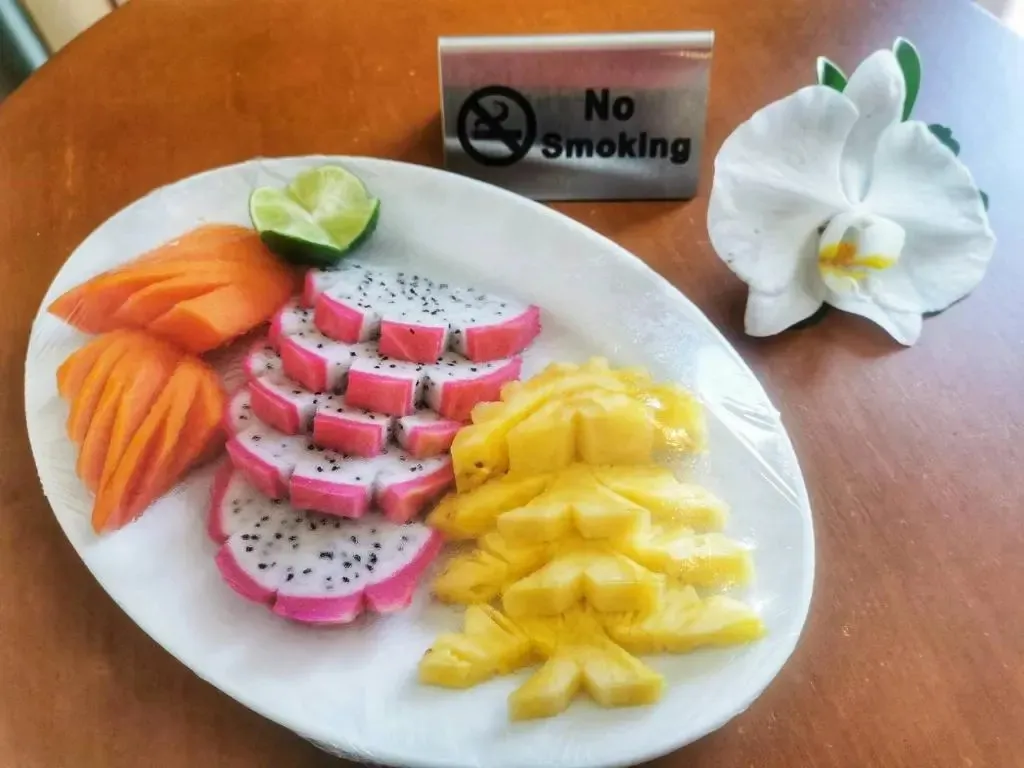 Assiette de fruits frais coupés et présentés avec une fleur et un panneau interdisant de fumer.