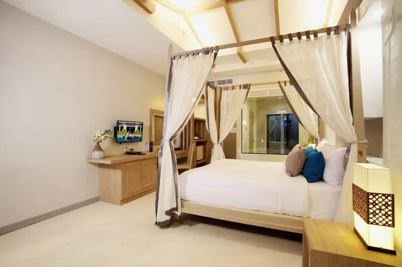 Une chambre lumineuse avec un grand lit à baldaquin et une décoration sobre.