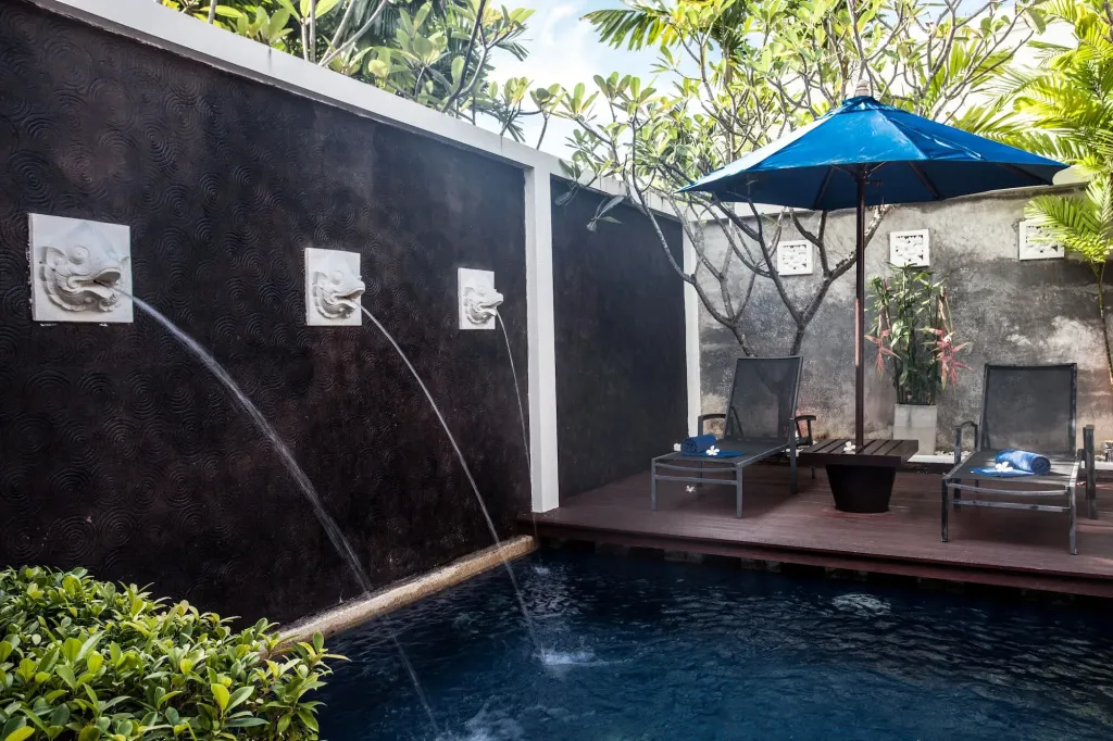 Espace de détente extérieur avec piscine et chaises longues ombragées.