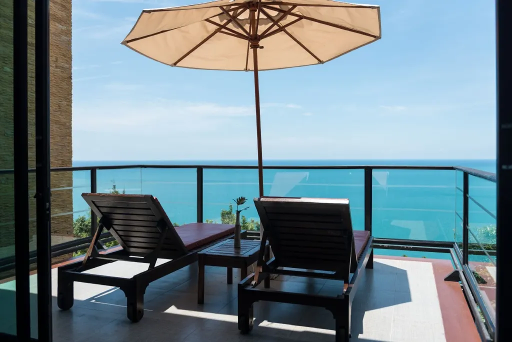 Deux transats et une table basse sur une terrasse avec vue sur la mer.