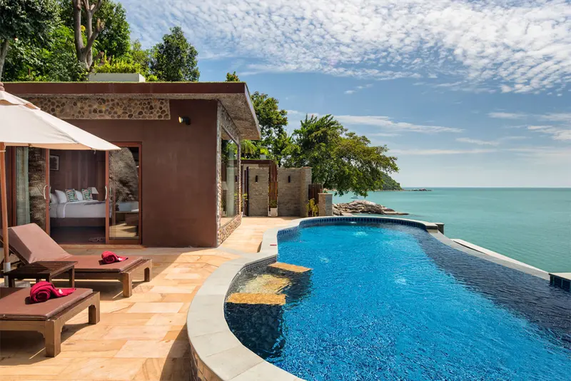 Une piscine à débordement offre une vue sur la mer depuis une terrasse aménagée.