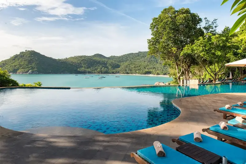 Une piscine à débordement surplombe une baie tropicale.