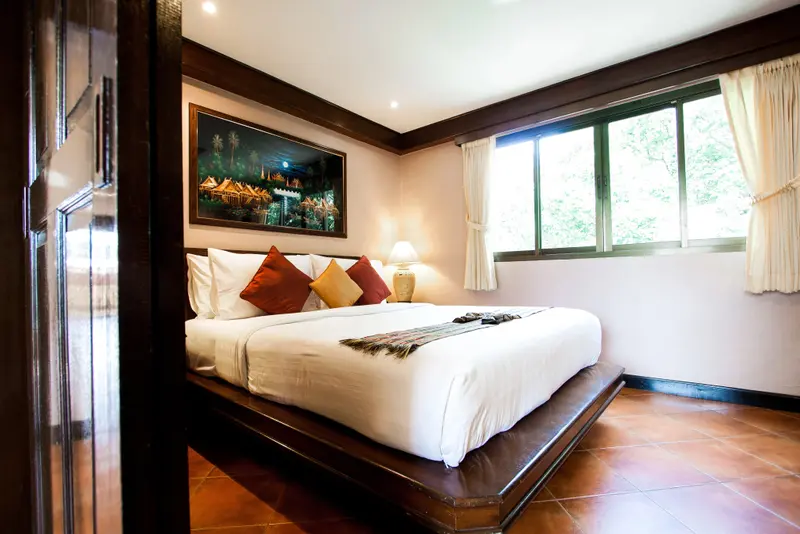 Une chambre lumineuse avec un grand lit recouvert de coussins.