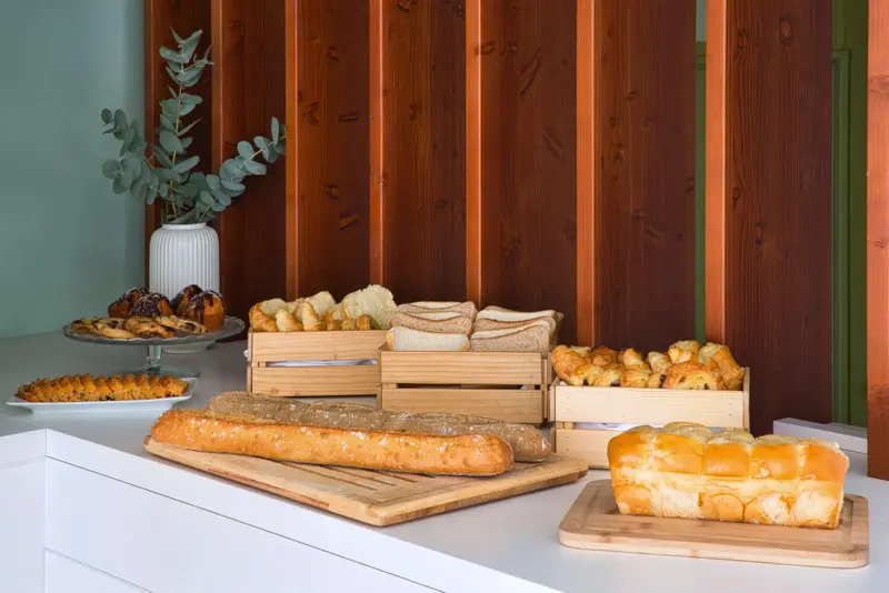 Présentation de viennoiseries et de pains frais sur un comptoir en bois.