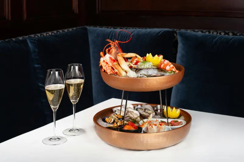 Une table est dressée avec un plateau de fruits de mer et deux coupes de champagne.