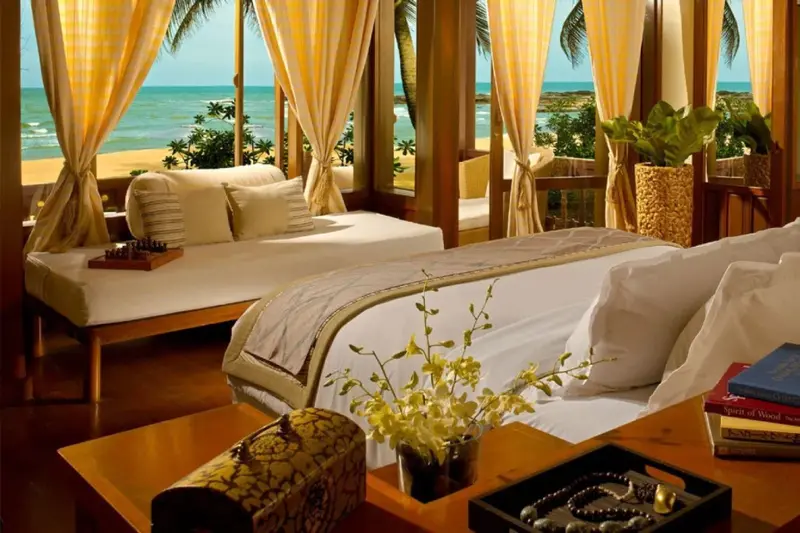Une chambre lumineuse s'ouvre sur une vue de plage et de mer.