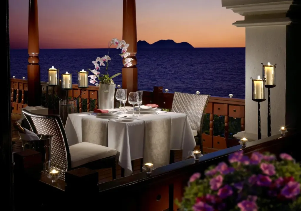 Table dressée pour un dîner romantique avec vue sur la mer au coucher du soleil.