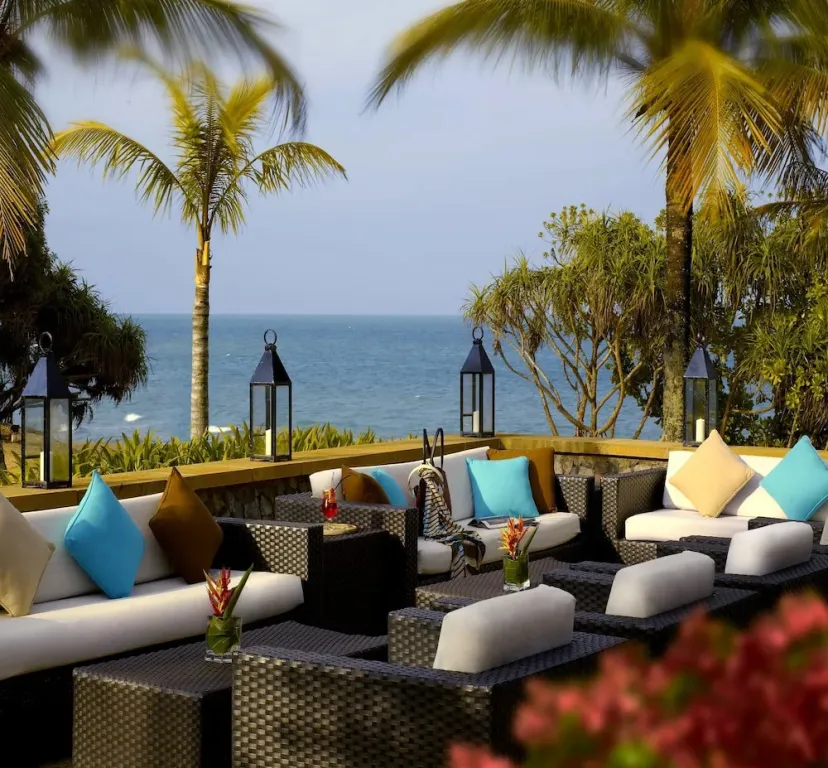 Espace de détente extérieur avec canapés et vue sur la mer.