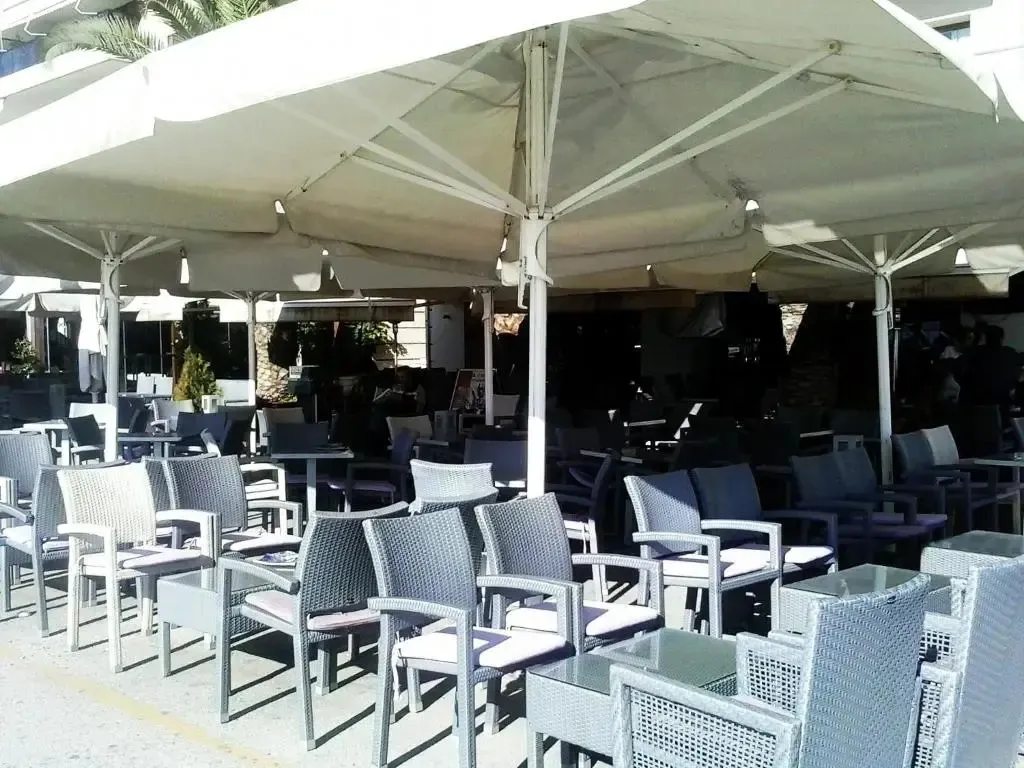 Terrasse ombragée avec tables et chaises en osier.