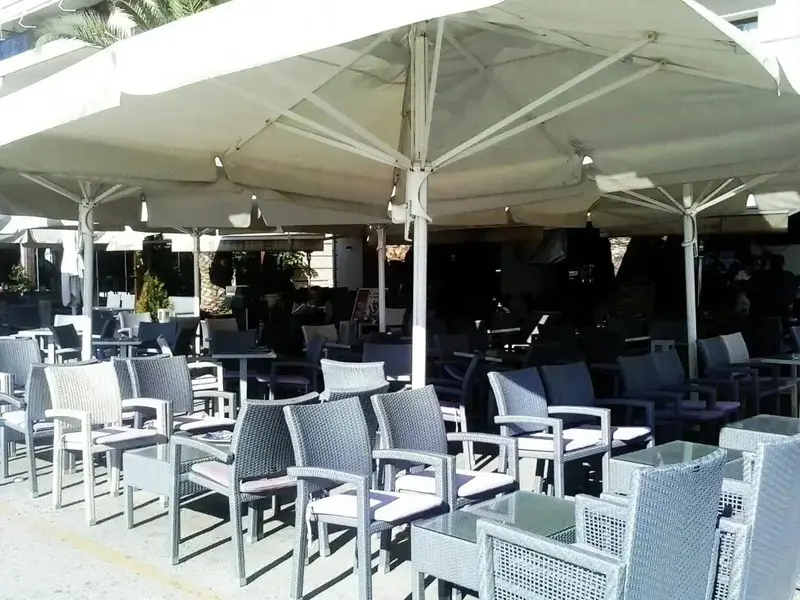 Terrasse ombragée avec tables et chaises en osier.