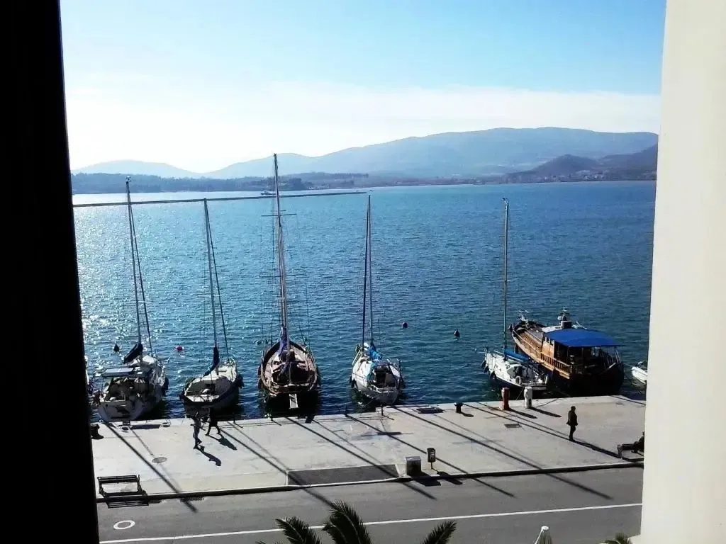 Des voiliers sont amarrés le long d'un quai ensoleillé face à la mer.