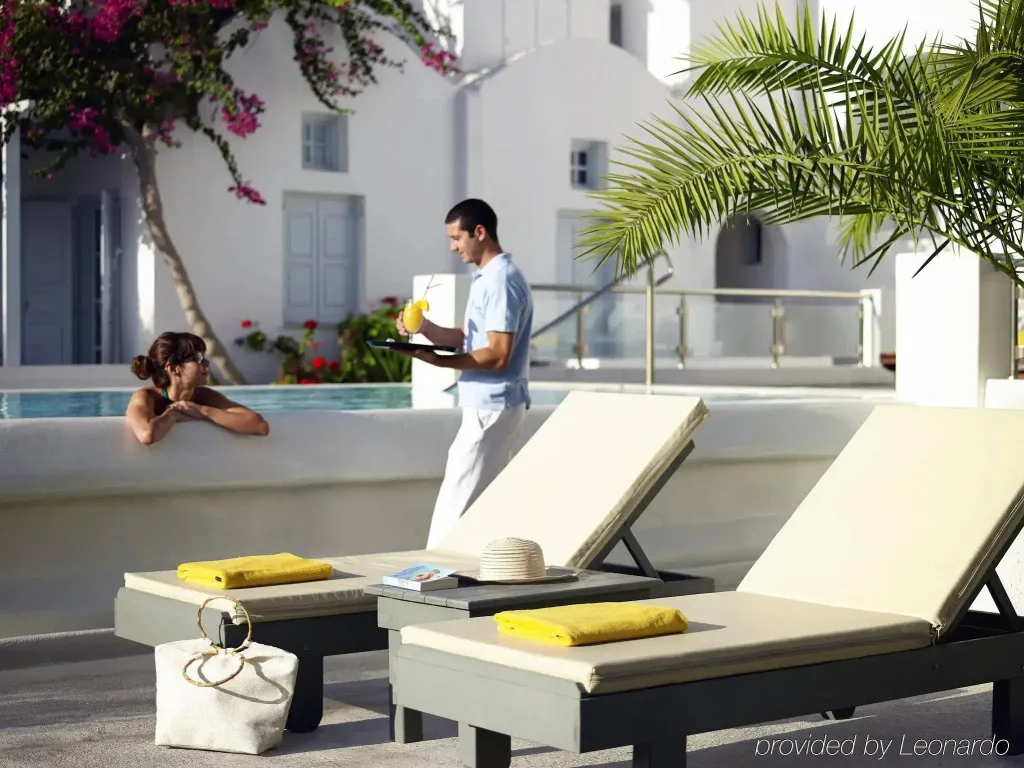 Un serveur apporte des boissons à une cliente allongée au bord d'une piscine.