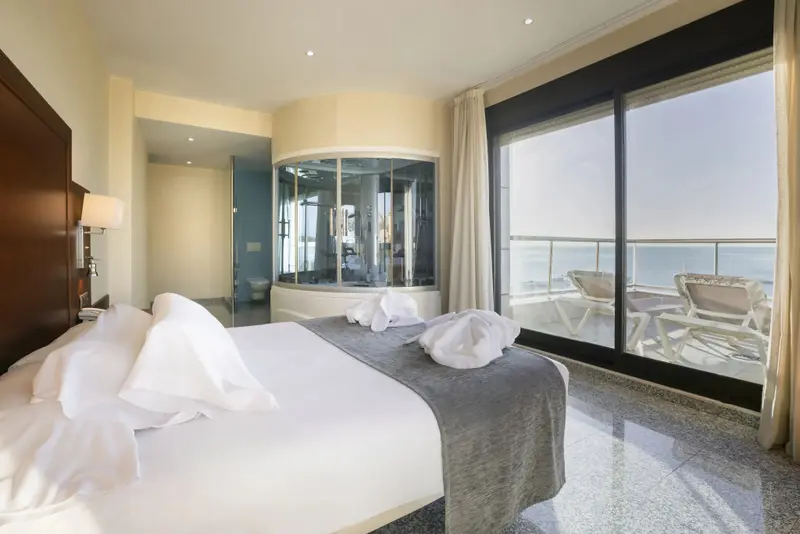 Une chambre lumineuse avec un grand lit et une salle de bain ouverte sur l'espace nuit.