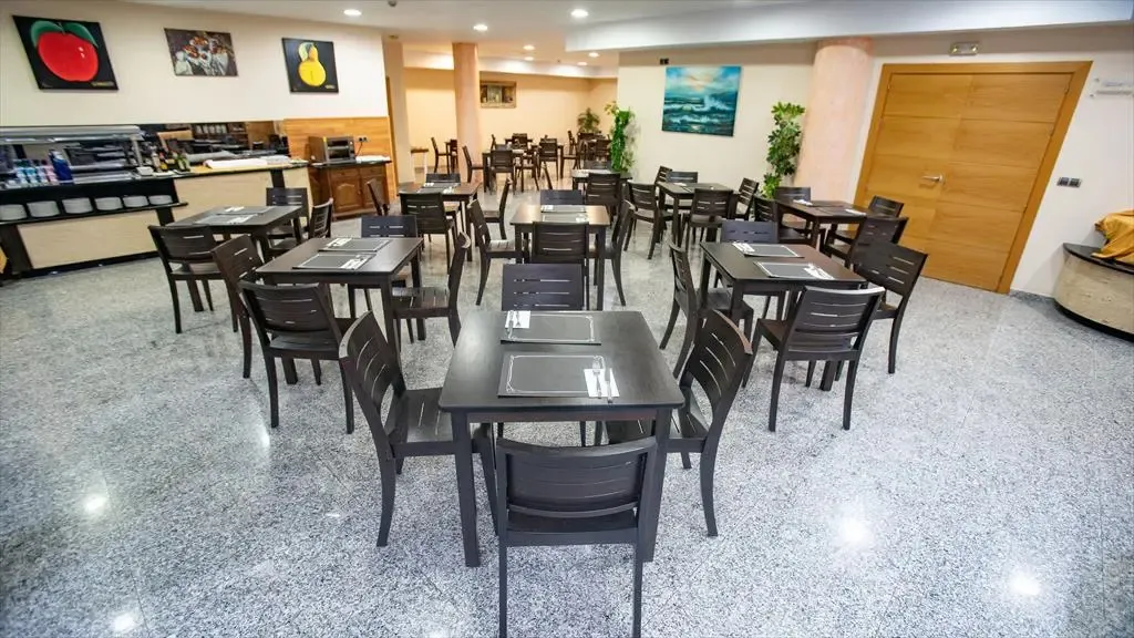 Une salle lumineuse est aménagée avec des tables et des chaises pour les repas.