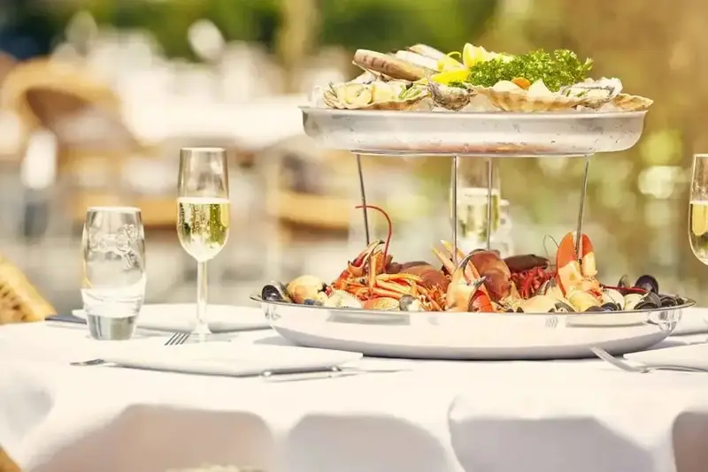 Une table dressée présente un plateau de fruits de mer frais et colorés.