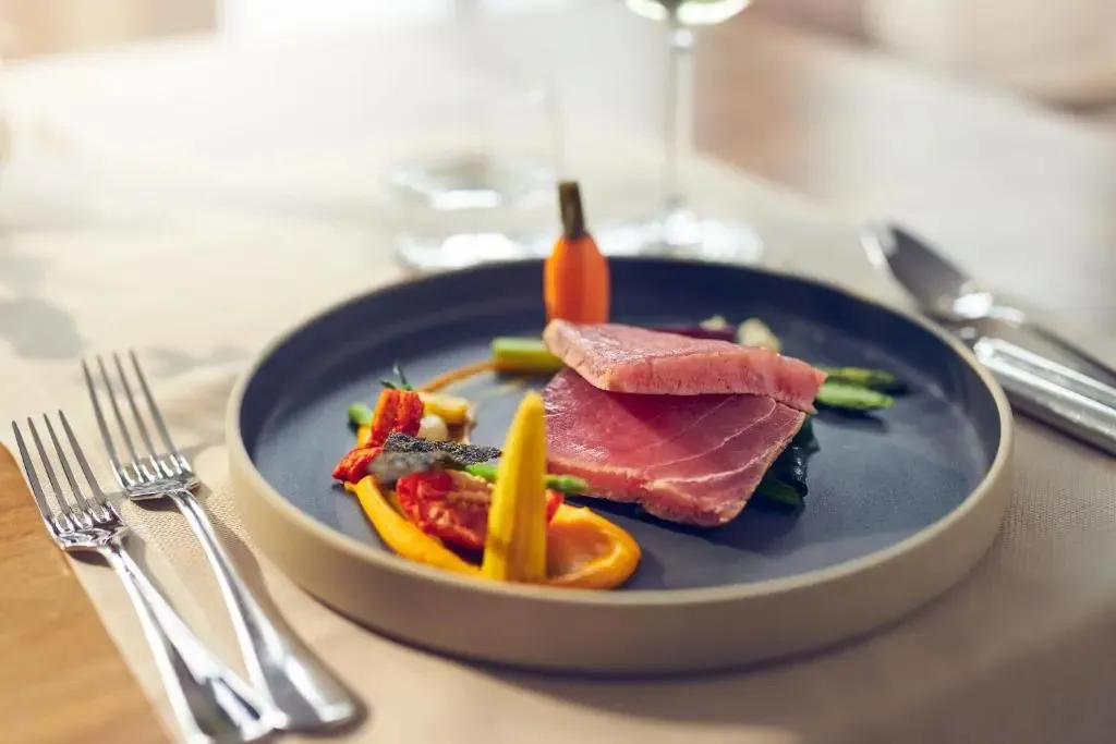 Assiette raffinée avec une présentation artistique de poisson et de légumes.