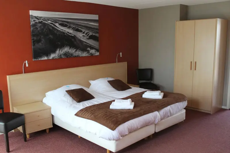 Une chambre lumineuse avec un grand lit et une décoration sobre.