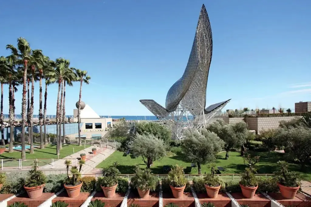 Jardin verdoyant avec sculpture contemporaine et vue sur la mer.