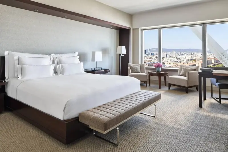 Une chambre lumineuse avec un grand lit et une vue sur la ville.