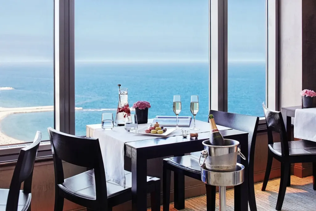 Une table est dressée devant une grande fenêtre donnant sur l'océan.