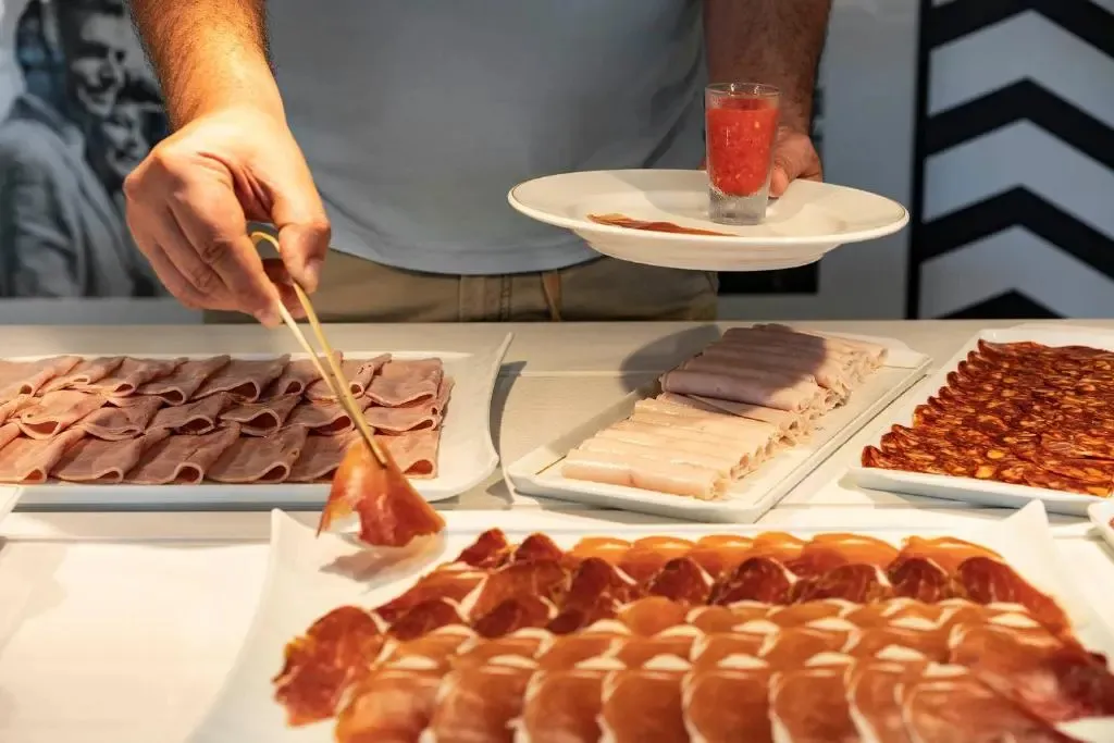 Un client se sert des tranches de charcuterie sur un buffet.
