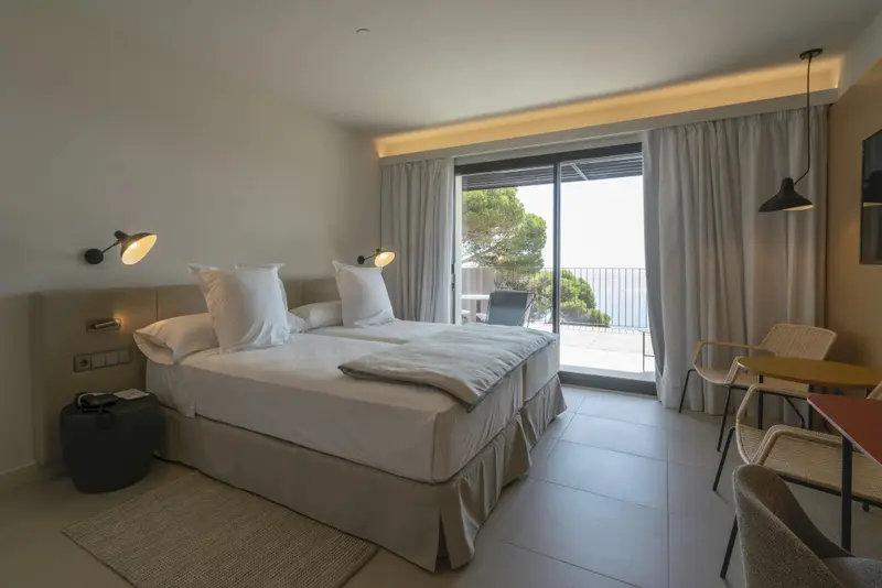 Une chambre lumineuse avec un grand lit et un accès à un balcon.