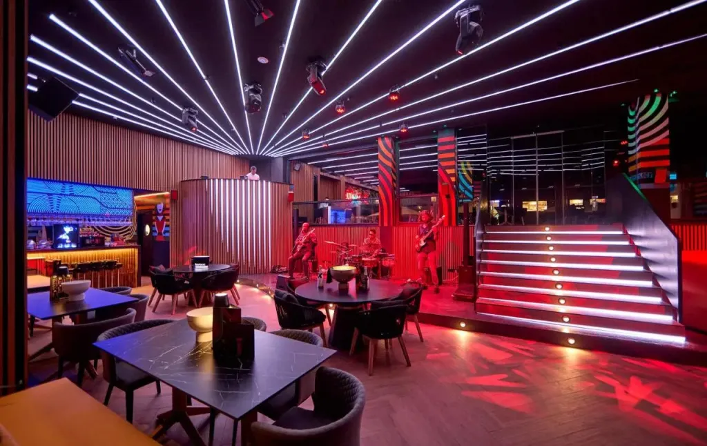 Une salle lumineuse avec des tables, des chaises et une scène musicale.
