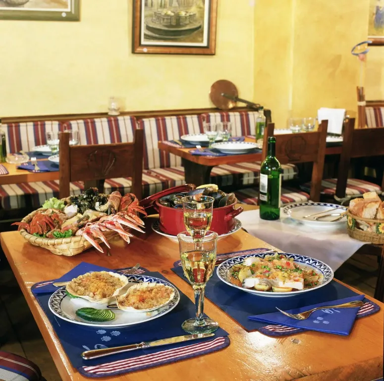 Une table est dressée avec des plats de fruits de mer et des boissons.