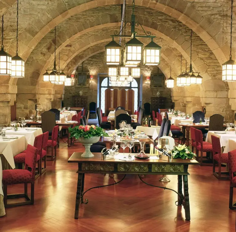 Une salle voûtée lumineuse accueille des tables dressées pour un repas.