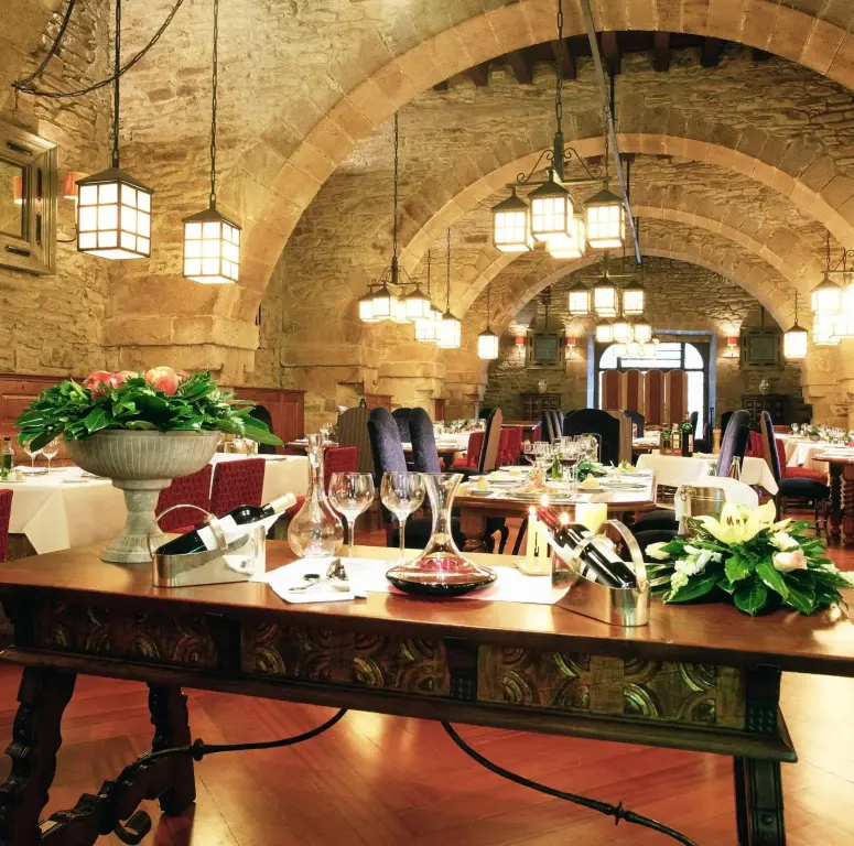 Une table richement dressée dans une salle voûtée éclairée par des lanternes.