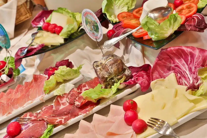 Présentation de charcuteries, fromages et légumes frais sur un buffet.