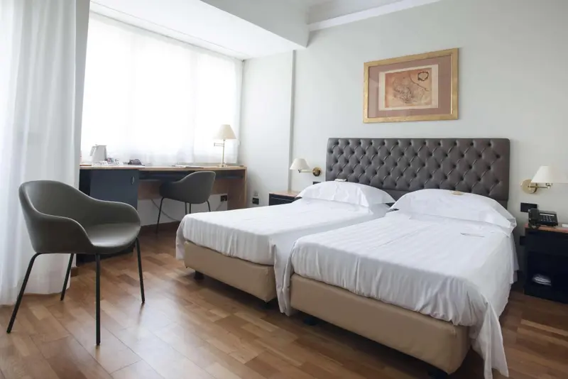 Une chambre lumineuse avec deux lits simples et un espace bureau.